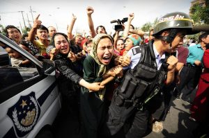 Ethnic Uygur women grab a riot policemen as they protest in Urumqi in China's far west Xinjiang province on July 7, 2009. Police fired clouds of acrid tear gas to disperse thousands of Han Chinese protesters armed with makeshift weapons, as chaos gripped this flashpoint city riven by ethnic tensions. Thousands of heavily armed police deployed across Urumqi, the capital of China's remote northwest Xinjiang region, but tensions spiked dramatically following weekend rioting that claimed at least 156 lives. TOPSHOTS AFP PHOTO/Peter PARKS (Photo credit should read PETER PARKS/AFP/Getty Images)